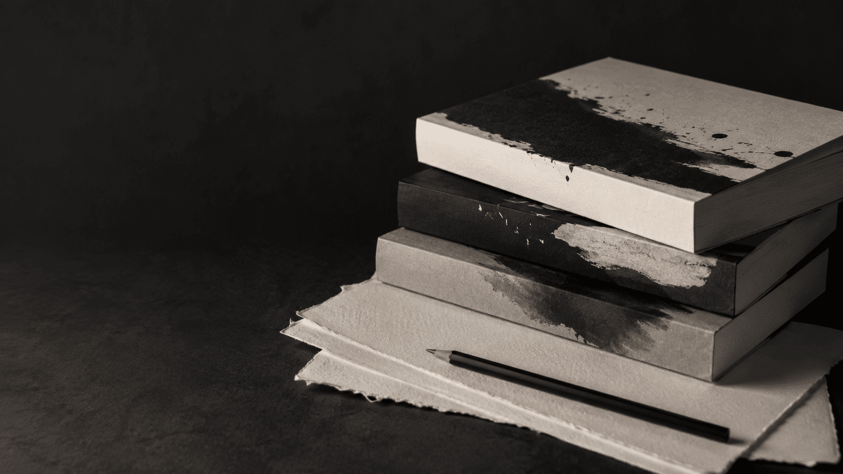 A stack of original paperback book concepts beside manuscript pages